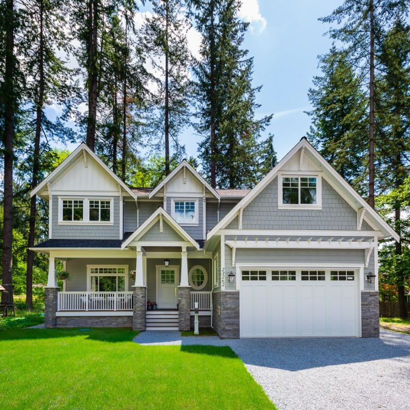 Front view of a charming family home nestled among lush trees, featuring multiple A-frame details that enhance its timeless, treehouse-inspired design.