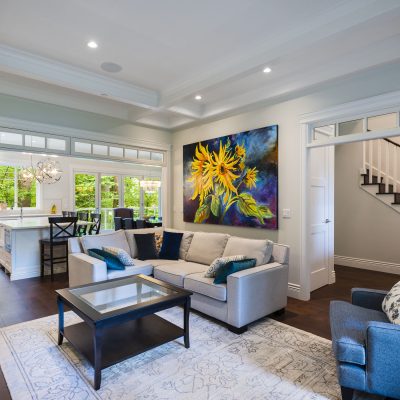View into an open concept living room and kitchen with a full wall of windows as the backsplash over the furthest countertops.