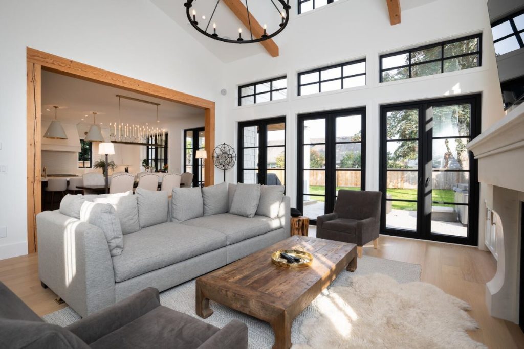 A vaulted ceiling in a large bright living room with multiple doors facing the backyard.